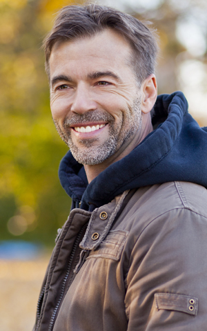 Smiling middle aged man shows off his new implant supported dentures in Rockwall.