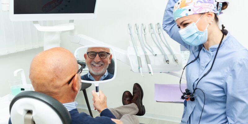 man smiling in mirror, happy with new dental implants