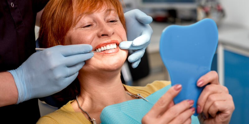 dentist in blue gloves showing a woman her new dental veneers