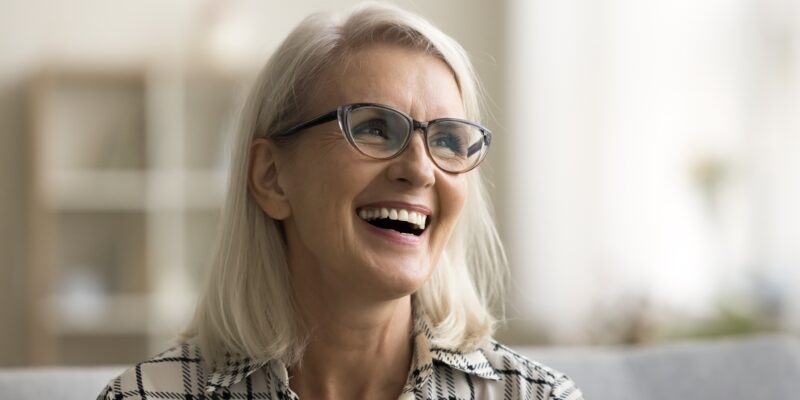 mature woman smiling on the couch, perfect new dental implants