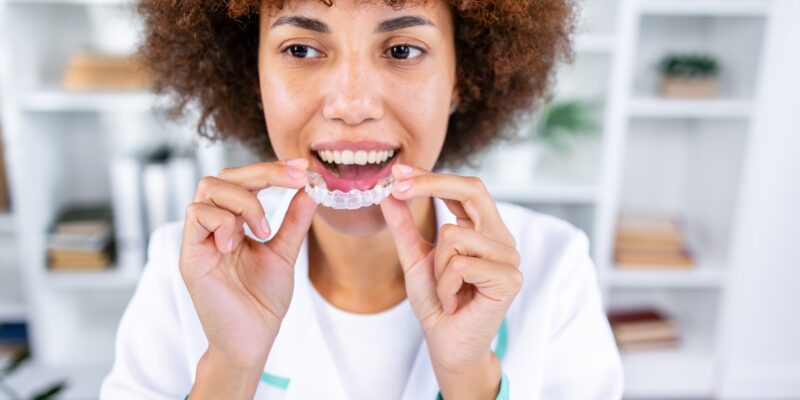 young woman holding up clear aligners, ready to place them
