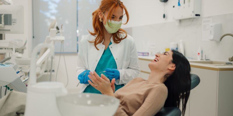 female dentist talking to a smiling female dental patient, modern dental office
