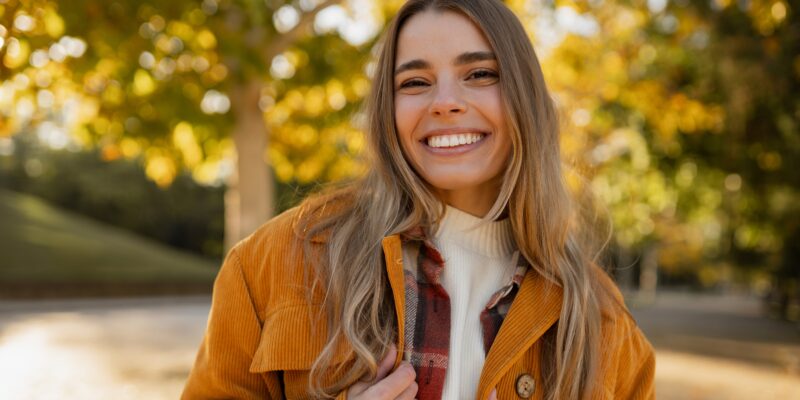 young woman smiling outdoors, perfect white smile