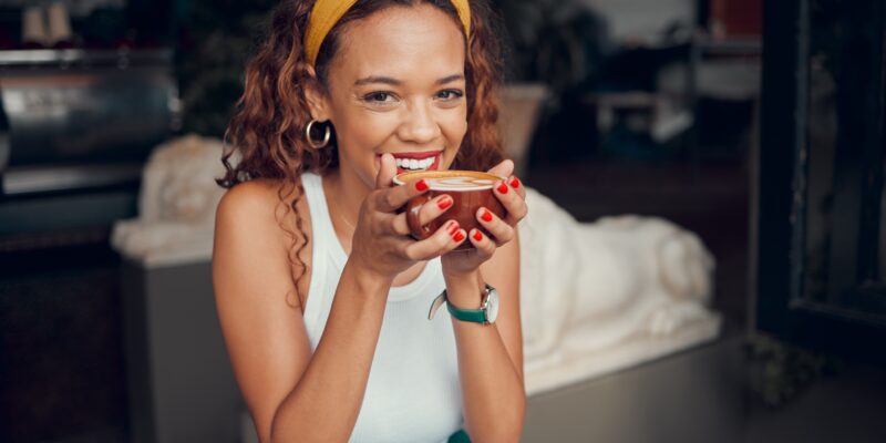 Smiling, happy young man enjoying a cup of tea at a café or coffee shop