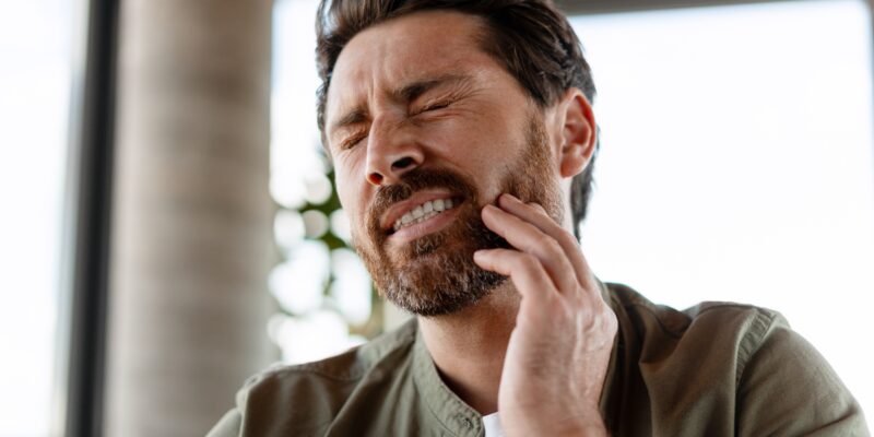 bearded man experiencing jaw pain, orofacial myofunctional disorder